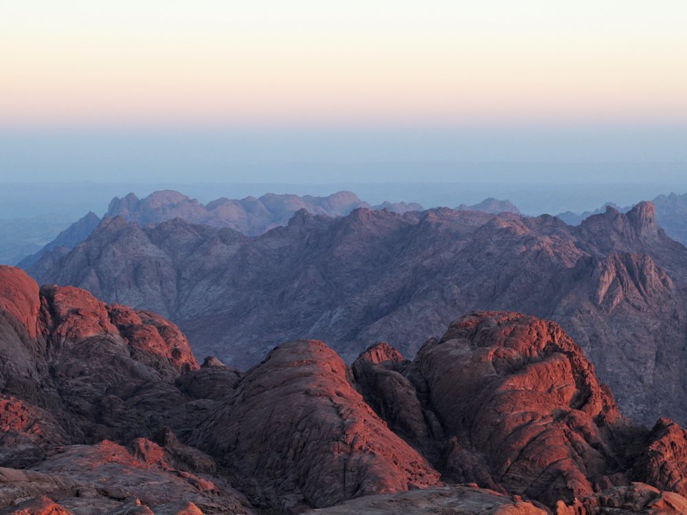 Sunrise breaking over the layered mountain ranges of the Sinai Peninsula, seen from the summit of Jebel Musa.